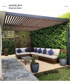 an outdoor living area with couches and potted plants on the side of it