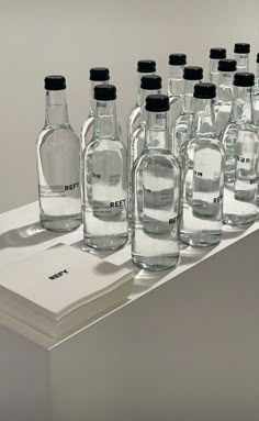 many empty glass bottles are lined up on a table with a white book in front of them