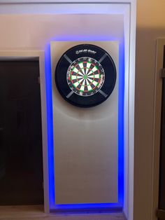 a dart board mounted to the side of a wall next to a neon blue light