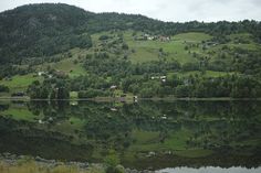 a lake surrounded by lush green hills and trees