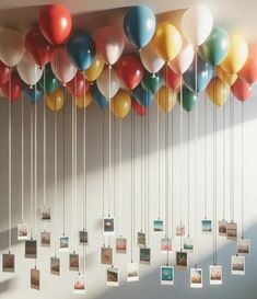 a bunch of balloons that are hanging from the ceiling with pictures attached to them,