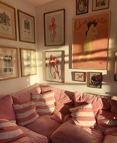 a living room filled with pink couches and pictures on the wall above their head