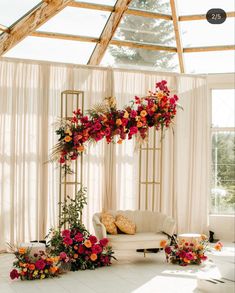 an arrangement of flowers and greenery is arranged on the floor in front of a couch