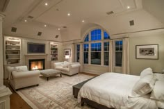 a large bedroom with white furniture and a fireplace