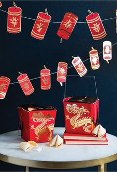 red and gold chinese lanterns hanging from string above table with books on white marble tabletop