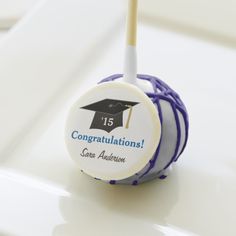 a blue and white graduation cake pops with congratulations sticker on it's top