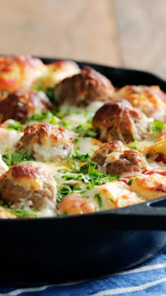 a pan filled with meatballs and cheese on top of a table