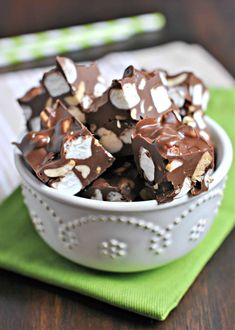 a white bowl filled with chocolate and marshmallows on top of a green napkin