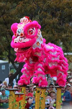 a pink and gold dragon statue in front of a crowd