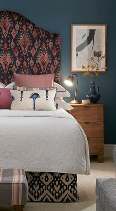 a bedroom with blue walls and an upholstered headboard on the side of the bed