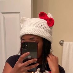 a woman taking a selfie in front of a mirror wearing a knitted hello kitty hat