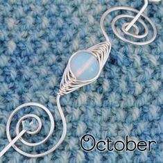 a close up of a wire wrapped necklace on top of a blue knitted surface