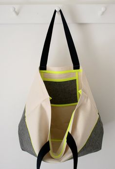 a handbag hanging from a hook on a white wall with black and yellow accents