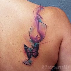 the back of a woman's shoulder with a butterfly and wine glass tattoo on it