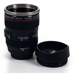 a camera lens coffee mug sitting on top of a white table next to a black cup