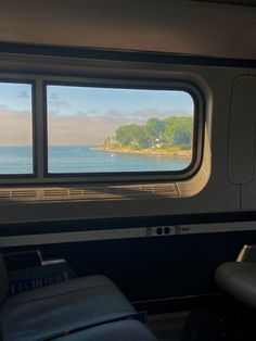 there is a window that looks out to the water from inside an empty train car