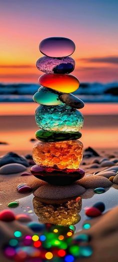 a stack of rocks sitting on top of a sandy beach next to the ocean at sunset