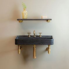 two black sinks with gold faucets on the wall