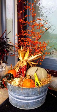 a metal bucket filled with pumpkins and gourds