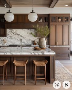 a large kitchen with marble counter tops and wooden stools in front of the island