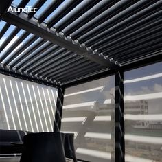 the inside of an awning with black chairs and tables in front of windows that have blinds on them