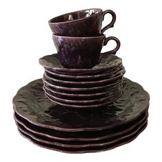 a stack of purple cups and saucers sitting on top of each other