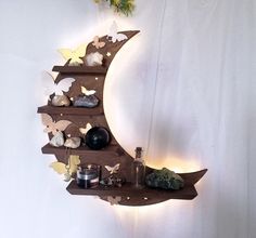 a wooden moon shelf with various items on it and butterflies flying around the space above