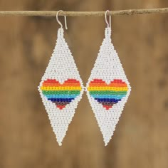 pair of white earrings with multicolored hearts on them hanging from a string against a wooden background