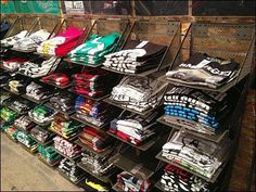 there is a rack full of t - shirts on the side of the street in front of a store