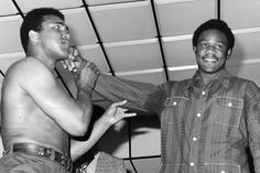 two men standing next to each other while brushing their teeth