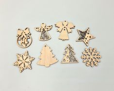 wooden christmas ornaments are arranged on a white surface with snowflakes and trees in the background