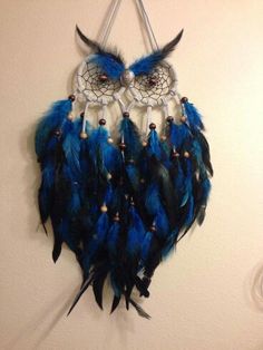 a blue and black dream catcher hanging on a wall next to a white wall with an owl's eye