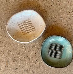 two bowls sitting on the ground next to each other, one with a comb in it