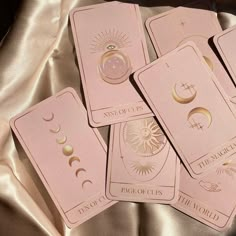 four pink tarot cards sitting on top of a gold cloth covered surface with symbols