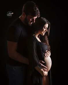 a pregnant woman is hugging her husband in the dark