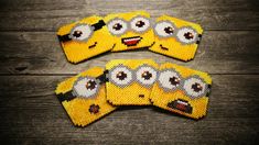 four pieces of yellow beaded coasters with cartoon characters on them, sitting on a wooden surface