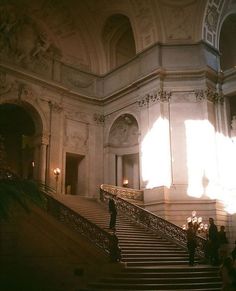 people are walking up and down the stairs in an old building with light coming through