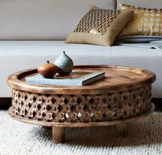 a coffee table sitting on top of a rug in front of a couch and pillows