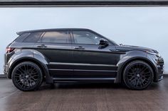 a black range rover parked in front of a white wall