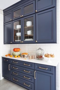 a kitchen with dark blue cabinets and white counter tops, gold pulls on the handles