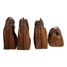 three pieces of brown leather bags sitting next to each other on a white surface with one bag in the middle