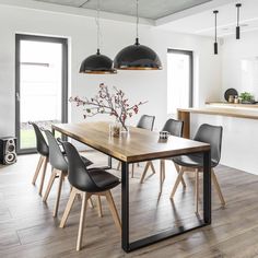 a dining room table with black chairs and lights