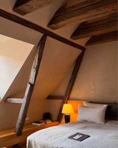 an attic bedroom with exposed wooden beams and white bedding