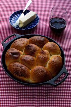 bread rolls in a cast iron skillet on a red and white checkered tablecloth