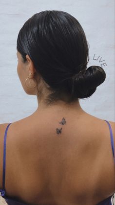 a woman with a butterfly tattoo on her upper back neck and behind her left shoulder