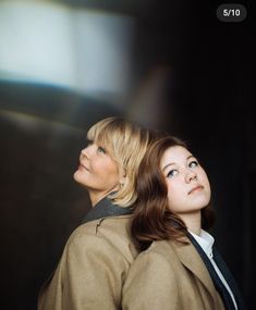 two women standing next to each other looking up