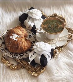 there is a croissant and cup on the plate next to each other with ribbons around it