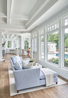 a living room filled with furniture and windows next to a wooden floor covered in white walls