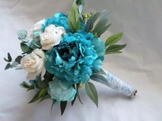 a bridal bouquet with blue and white flowers on a white sheeted bedding