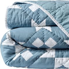 two blue and white quilted bedspreads stacked on top of eachother